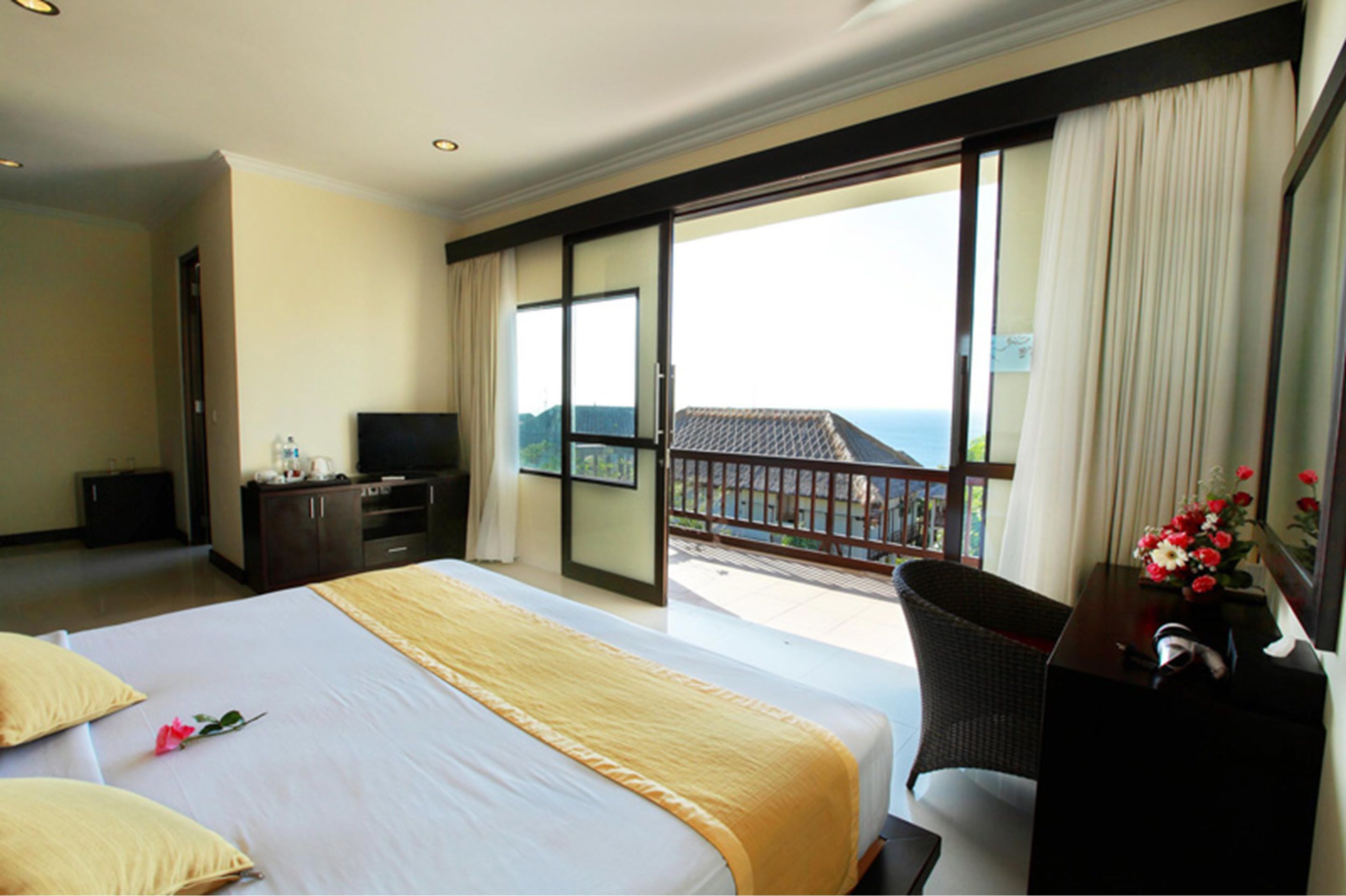 Une chambre d’hôtel avec un grand lit, un bureau, une télévision et un balcon avec vue.