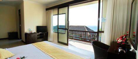 Une chambre d’hôtel avec un grand lit, un bureau, une télévision et un balcon avec vue.