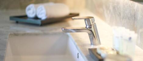 A bathroom sink with a chrome faucet, a towel on a tray, and a soap dispenser.