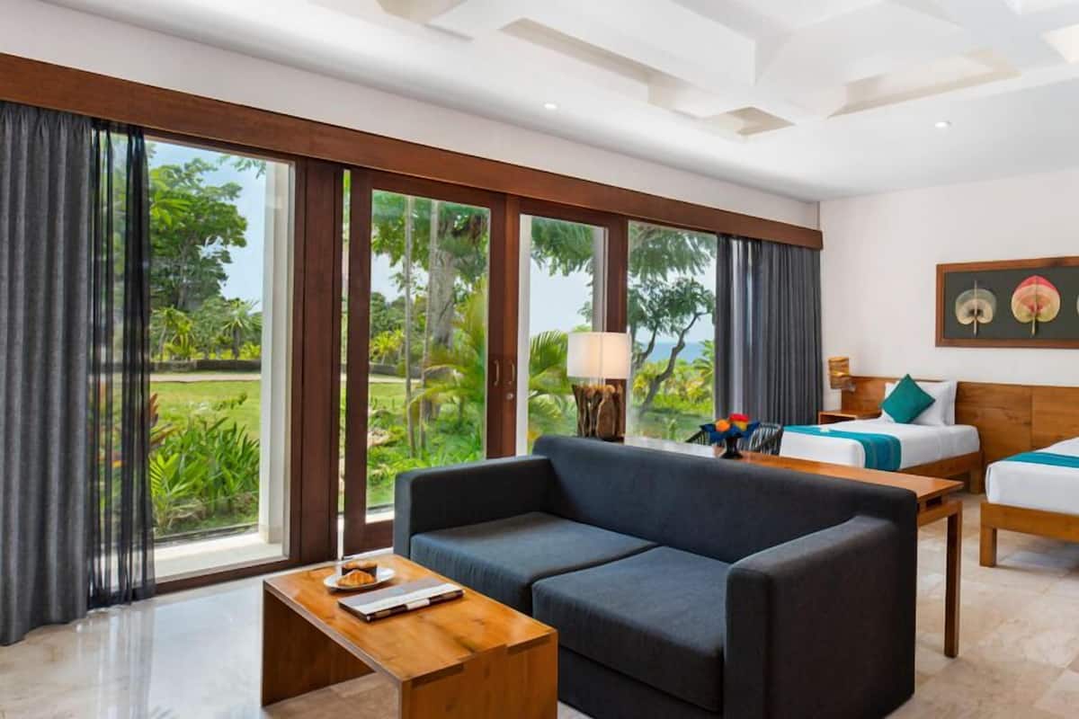 A hotel room with a large sliding glass door, two beds, a sofa, and a small table.