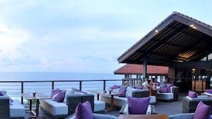 A seaside patio with outdoor seating and a view of the ocean. - Blue Point Resort and Spa (Pecatu)
