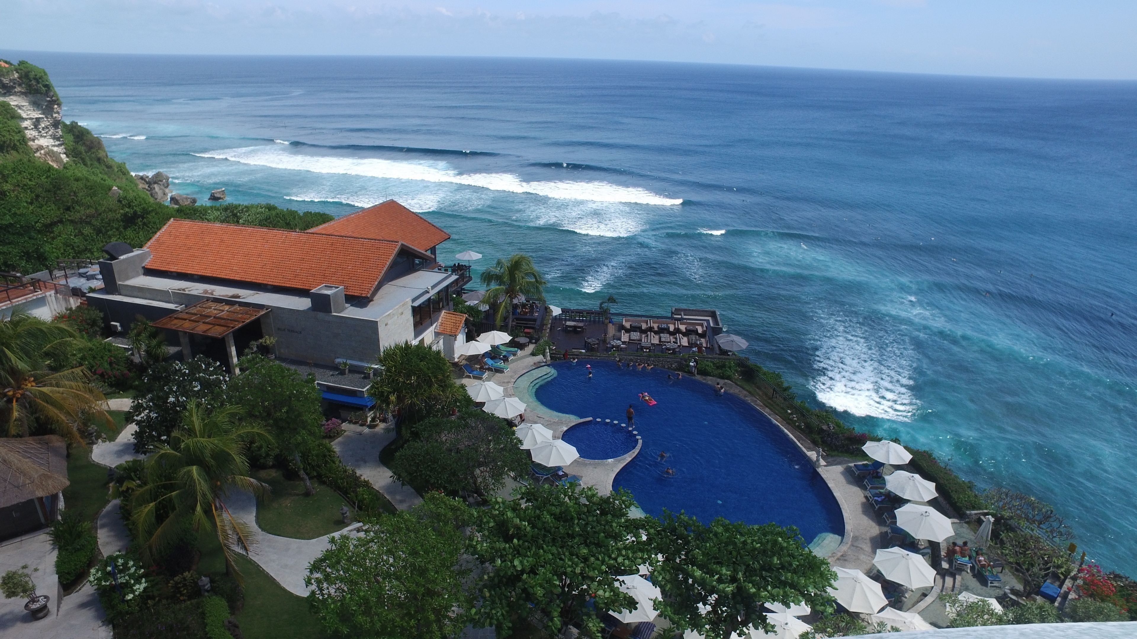 Resort com uma piscina grande, praia e vista para o oceano.
