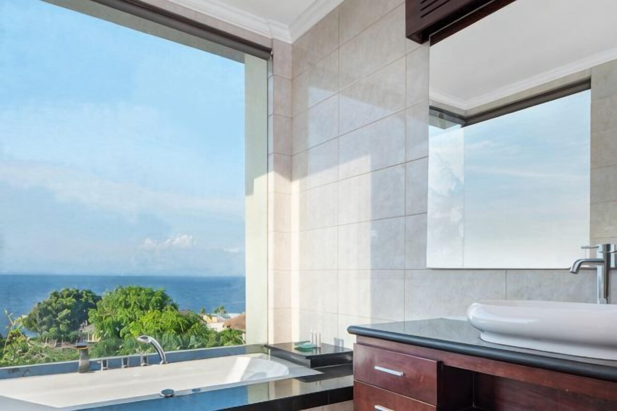 A bathroom with a large window, a sink, and a mirror.