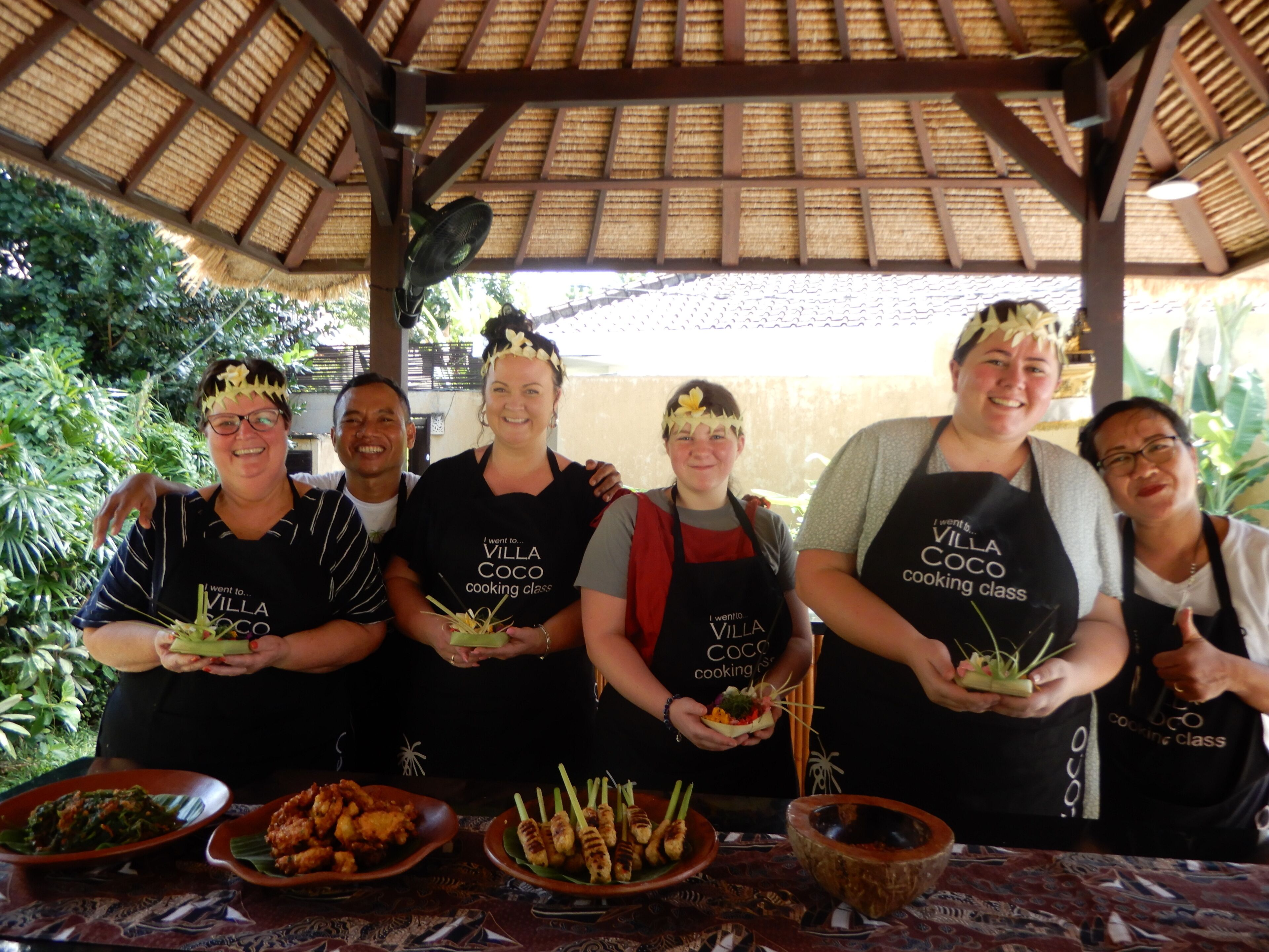 A group of people in aprons at a cooking class, holding food items.