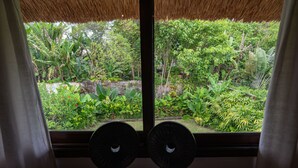 A room with a large window overlooking a lush garden. - Villa Coco (Seminyak)
