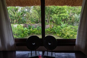 A room with a large window overlooking a lush garden.