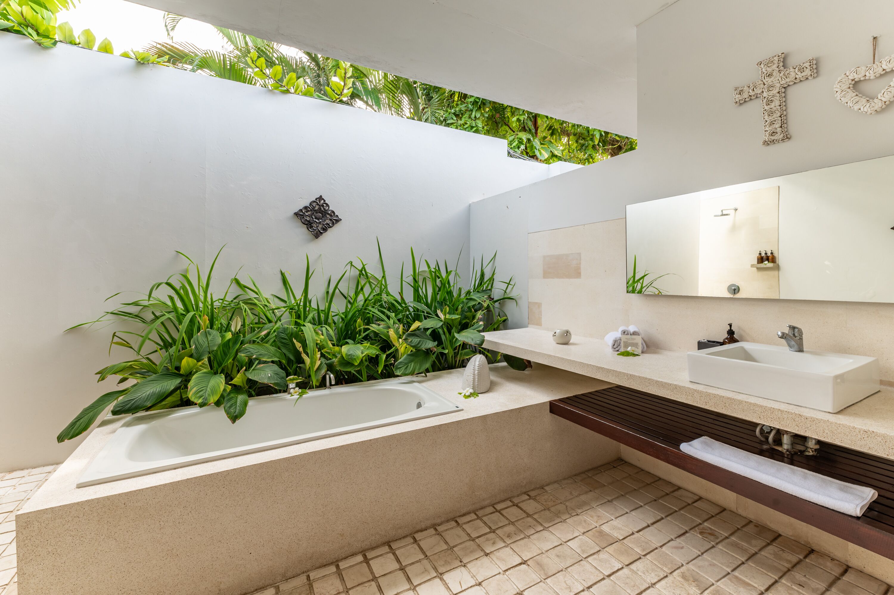 A modern bathroom with a large bathtub, a white vanity, a mirror, and a wall-mounted plant arrangement.