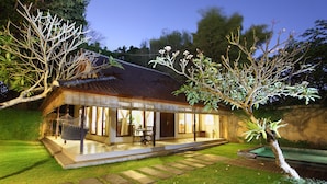 A house with a tiled roof, a visible swimming pool, and a well-maintained lawn. - Villa Coco (Seminyak)