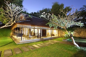 A house with a tiled roof, a visible swimming pool, and a well-maintained lawn.
