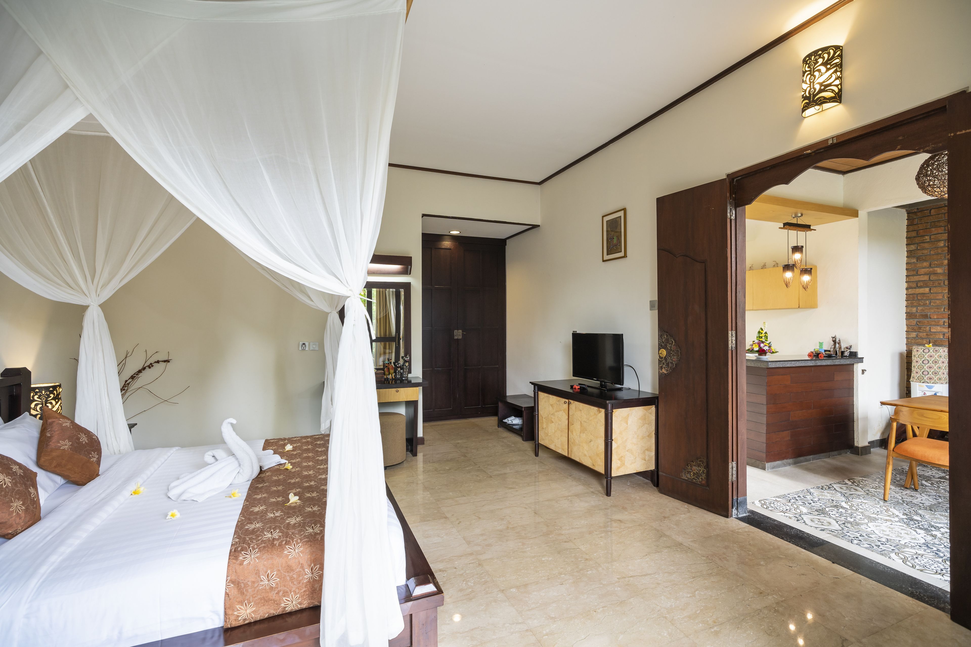 Ein Hotelzimmer mit Bett, Schreibtisch, Fernseher und einem durchgegangenen Tür sichtbaren Badezimmer.