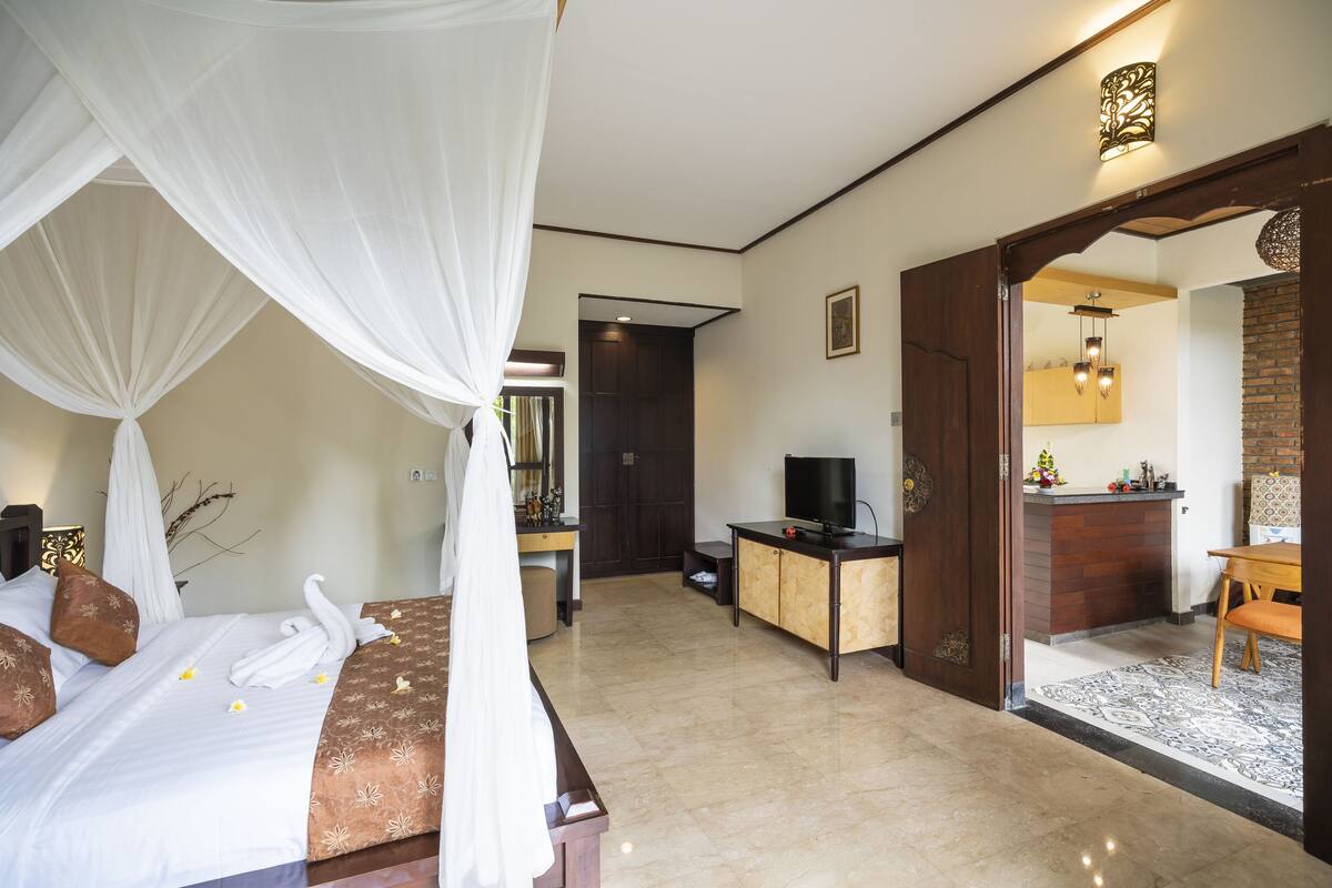 Ein Hotelzimmer mit Bett, Schreibtisch, Fernseher und einem durchgegangenen Tür sichtbaren Badezimmer.