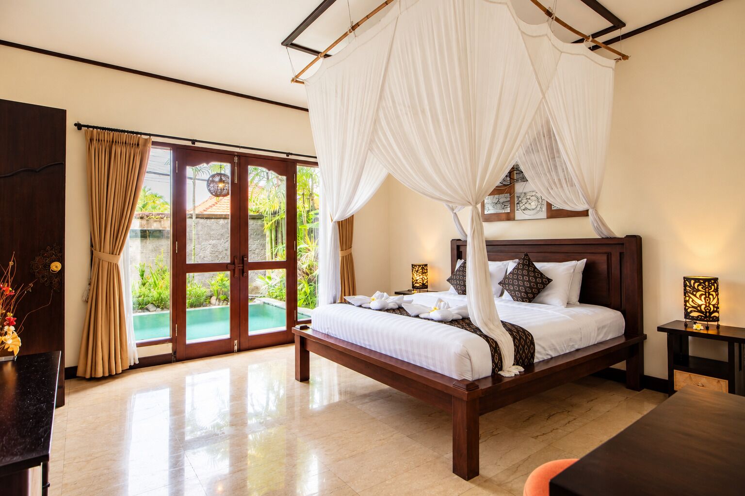 A bedroom with a four-poster bed, a view of a swimming pool, and a wooden floor.
