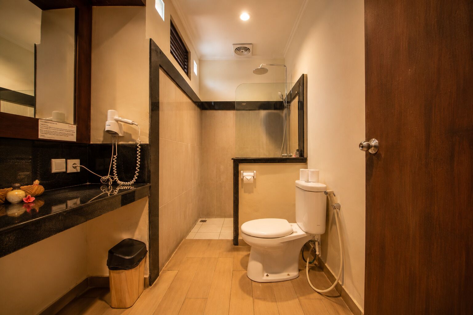 A compact bathroom with a toilet, a shower, and a vanity with a mirror.