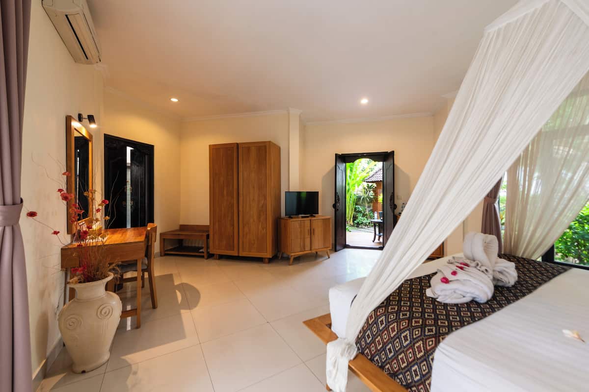Ein Hotelzimmer mit Bett, Schreibtisch, Fernseher, Kleiderschrank und Blick ins Freie.