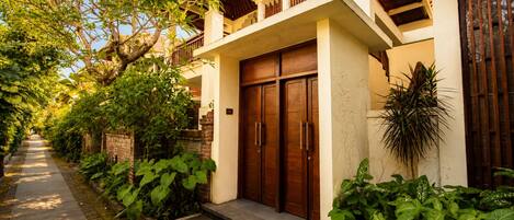 A two-story building with a wooden door and a balcony.