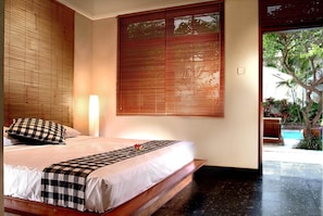 Une chambre à coucher avec un lit, une couvre-lit à carreaux et une grande fenêtre avec des stores.