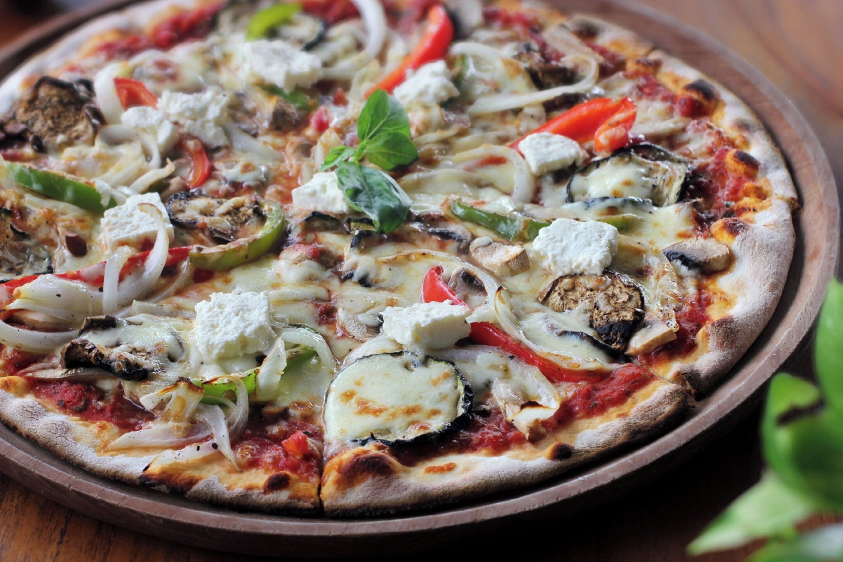 A pizza with various toppings on a wooden tray.