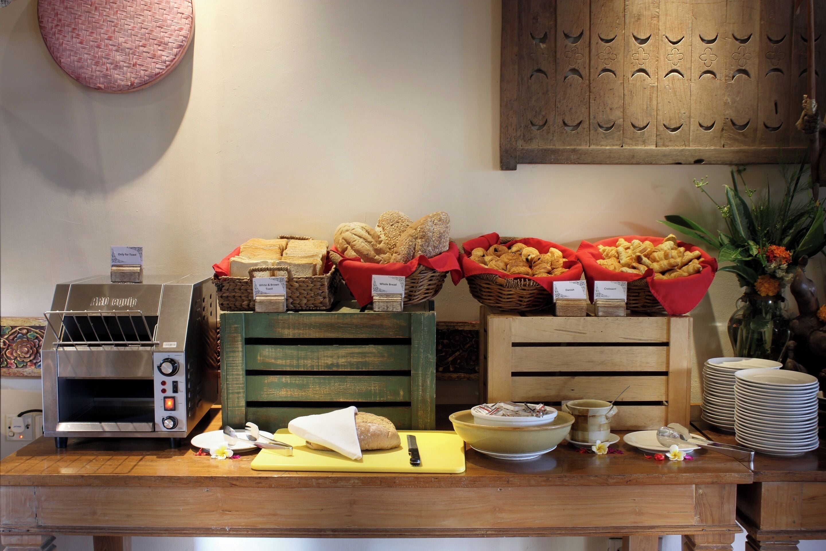 Een ontbijtbuffet met een broodrooster, brood, gebak en diverse kommen en borden.