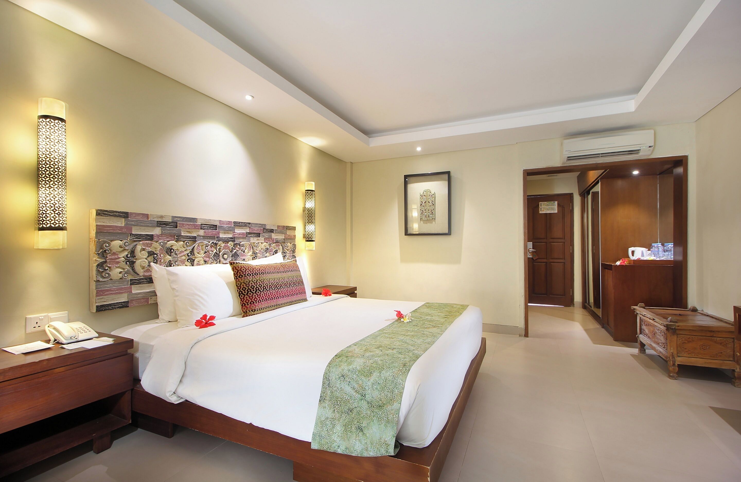 A hotel room with a large bed, bedside tables, a wall-mounted phone, and a framed picture.