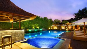A swimming pool with a wooden deck, lounge areas, and a thatched roof structure. - AlamKulKul Boutique Resort Kuta Bali (Legian)