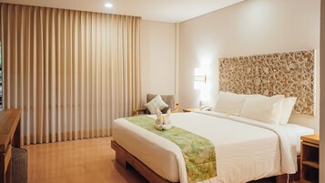 A hotel room with a large bed, a wooden nightstand, a desk, and a chair.