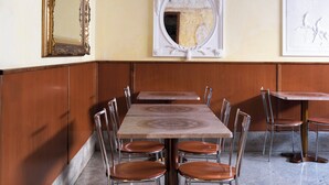 Un coin repas avec une longue table en bois et des chaises, un miroir décoratif et une œuvre d’art encadrée accrochée au mur.