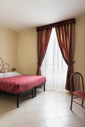 A room with a bed, a chair, and a window with curtains. - Stromboli (Rome)