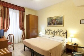 A hotel room with a bed, a desk, a chair, a wardrobe, a painting on the wall, and a lamp on the bedside table. - Stromboli (Rome)
