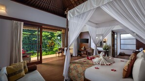 A bedroom with a canopy bed, a television, a desk, and a view of lush greenery. - Kori Ubud Resort (Ubud)