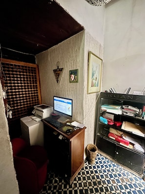 Um pequeno escritório com um computador de mesa, uma impressora e um armário de arquivo.