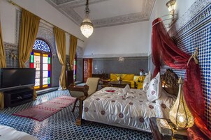 Un dormitorio amplio con una cama grande, un televisor y un candelabro decorativo.