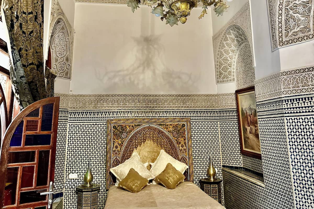 A room with a large bed, ornate ceiling, and patterned walls.