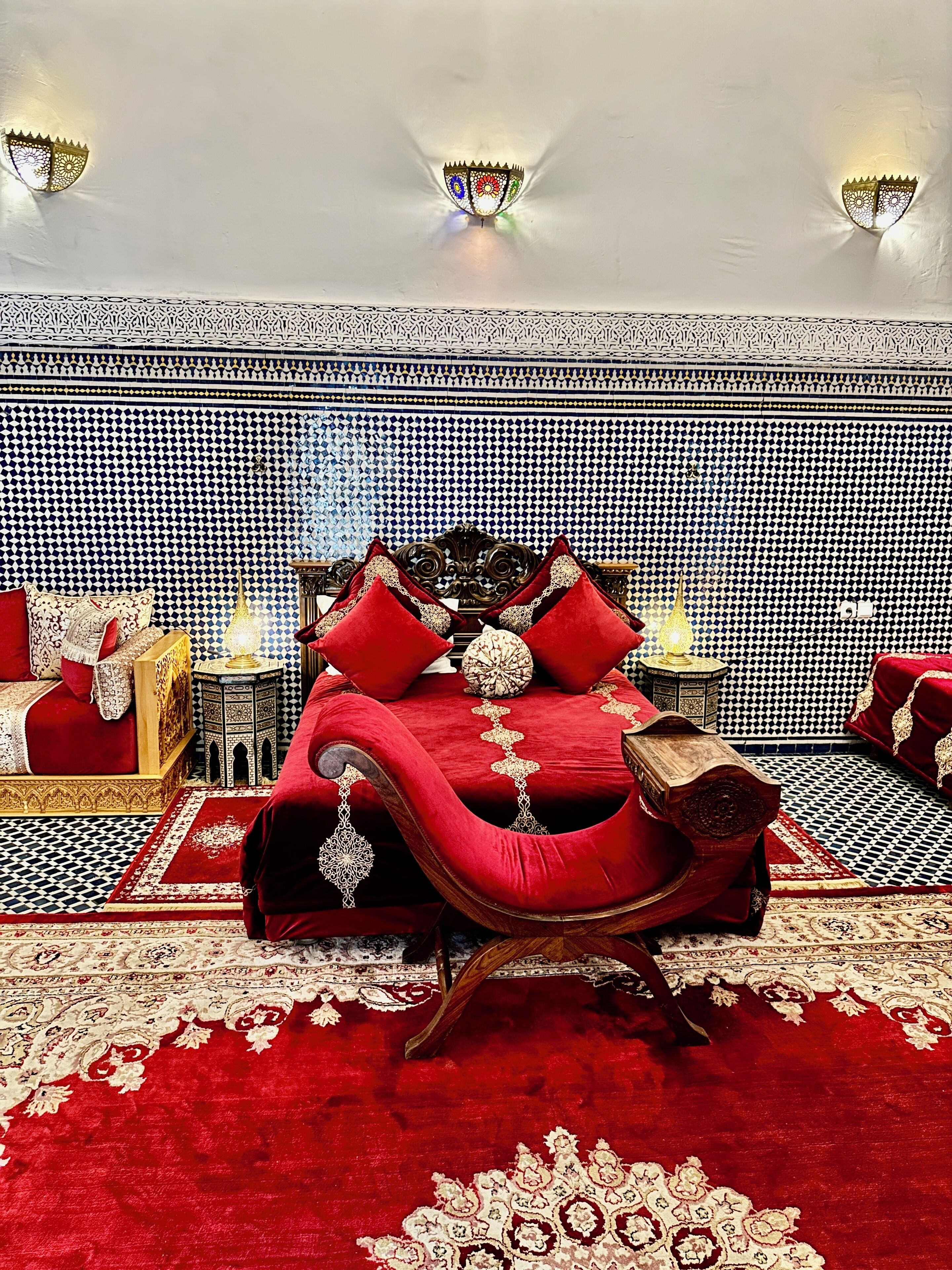 A room with a large bed, ornate wall decor, and patterned rugs.