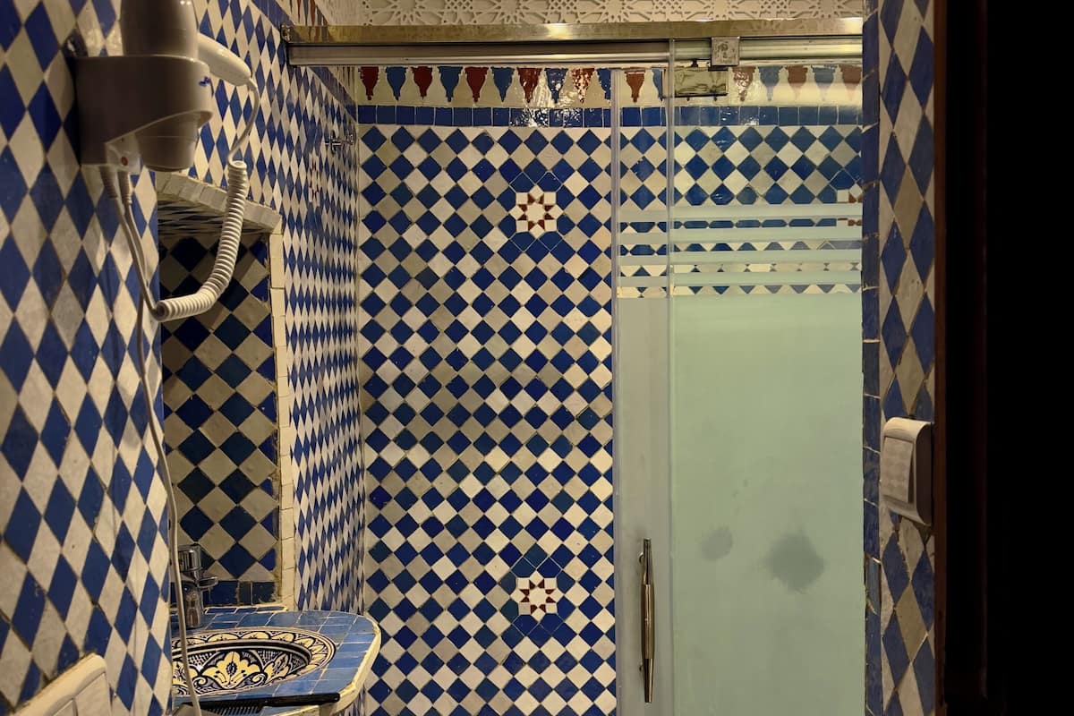 A bathroom with a checkered tile pattern, a towel rack, and a shower area.