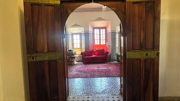 Una puerta que da a una habitación con piso estampado y un sofá rojo.