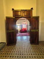 Uma porta que dá para um quarto com um piso estampado e um sofá vermelho.