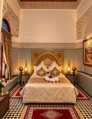 A luxurious bedroom with a large bed, ornate headboard, and intricate tile work. - Riad Damia Suite &Spa (Fes)