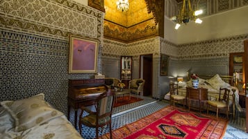 Una habitación con detallados trabajos en azulejos, una alfombra roja grande y muebles tradicionales.
