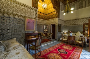 Quarto com detalhada azulejaria, tapete vermelho grande e mobiliário tradicional.