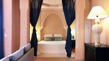 A bedroom with a bed, curtains, a lamp, and a nightstand.