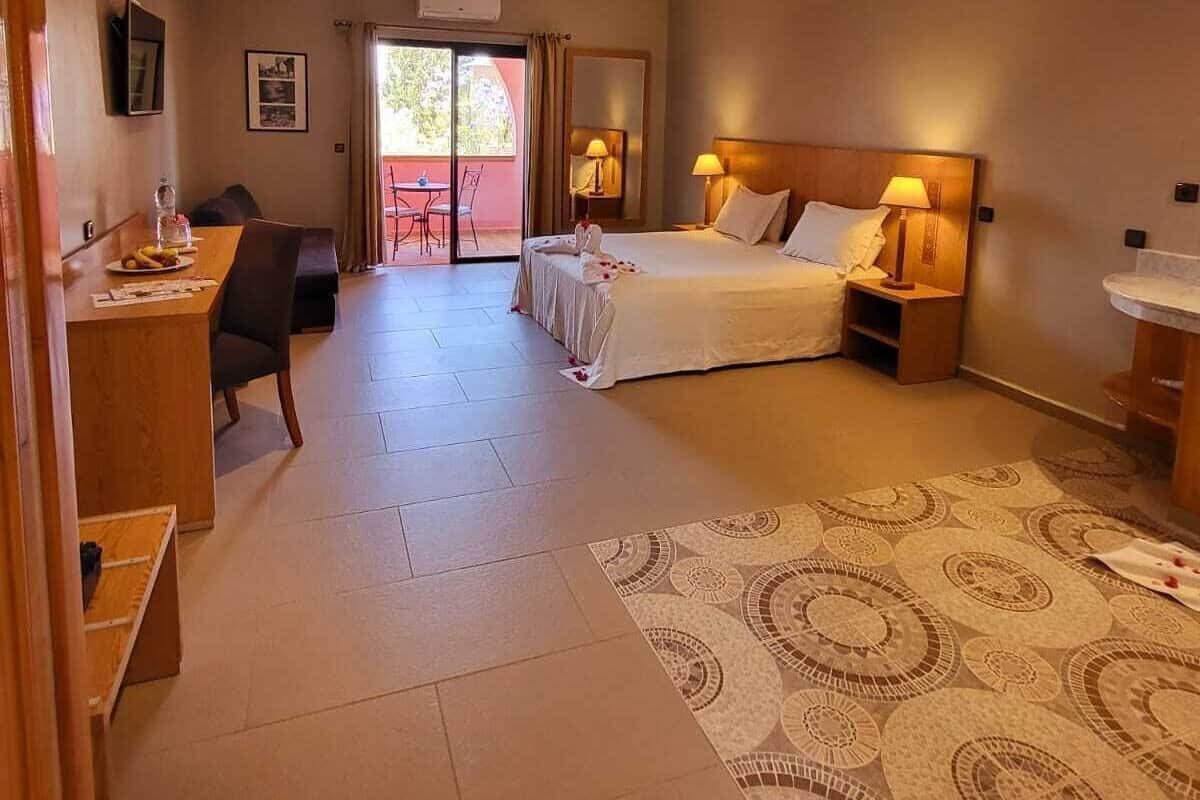 Une chambre d’hôtel comprenant un lit, des tables de chevet, un bureau, une chaise et un tapis à motifs.