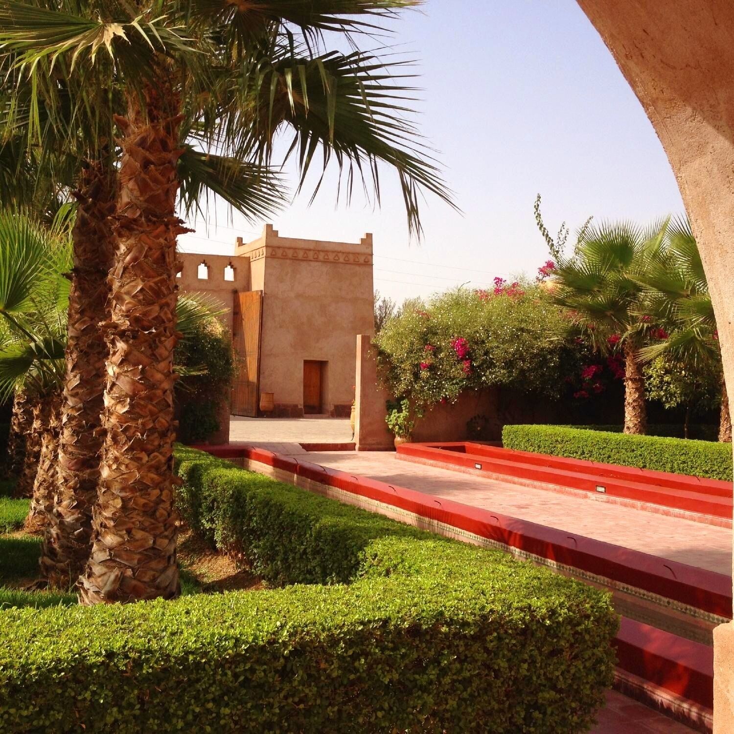 Un patio con palmeras, un sendero y un edificio de diseño tradicional.