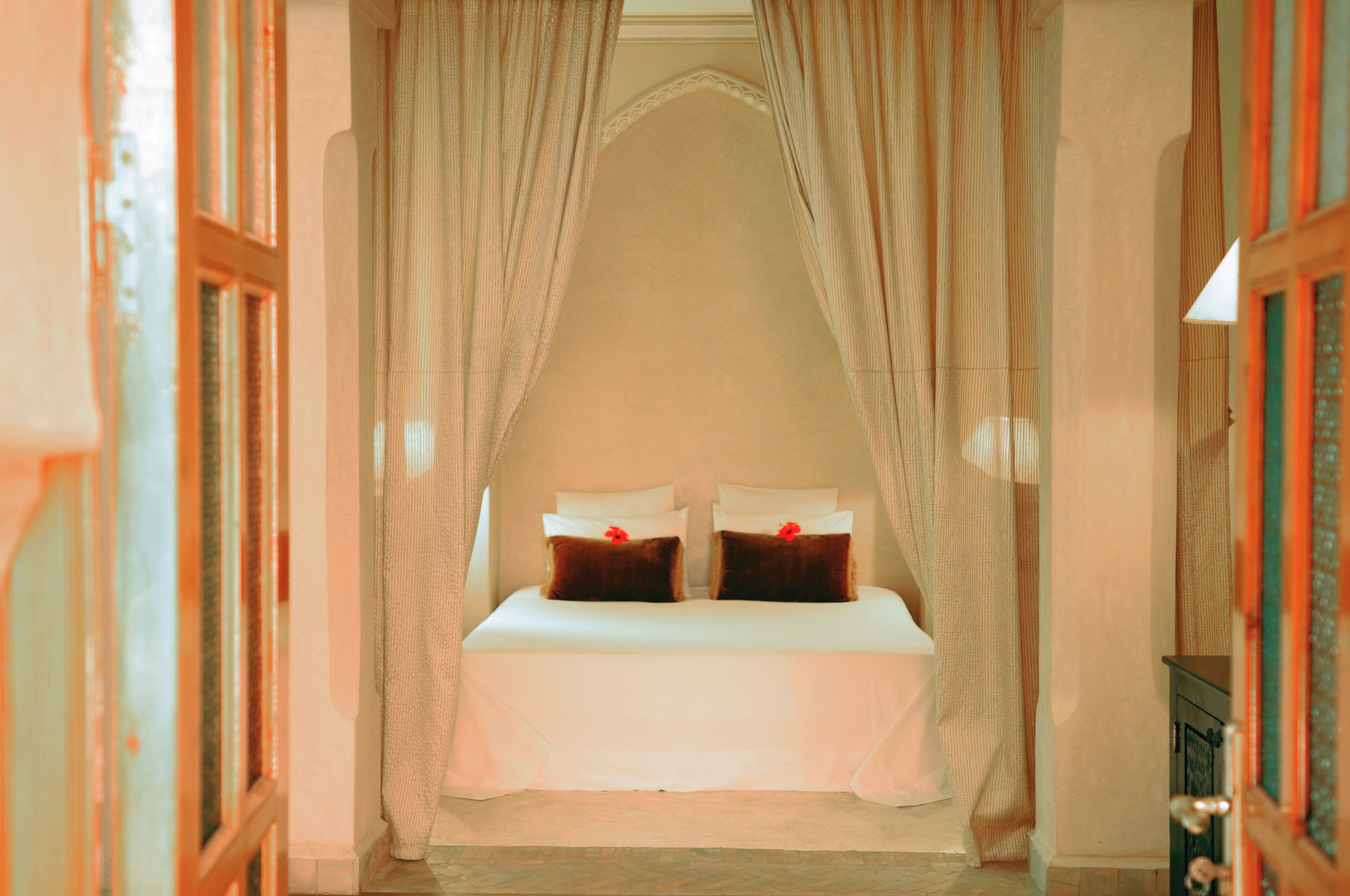 A room with a bed under a canopy, a door on the left, and a wall on the right.