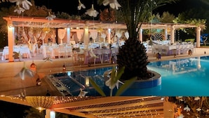 Ein Essbereich im Freien mit gedeckten Tischen für eine festliche Veranstaltung, ein Pool mit dekorativem Mittelstück und eine überdachte Sitzgelegenheit mit Lichterketten.