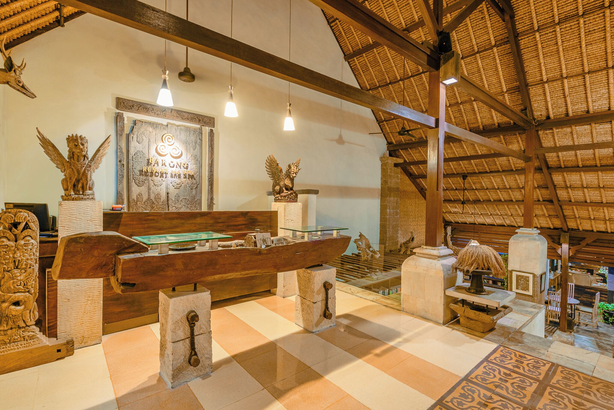 Una habitación con un banco de madera, una vitrina de cristal y un techo de paja.