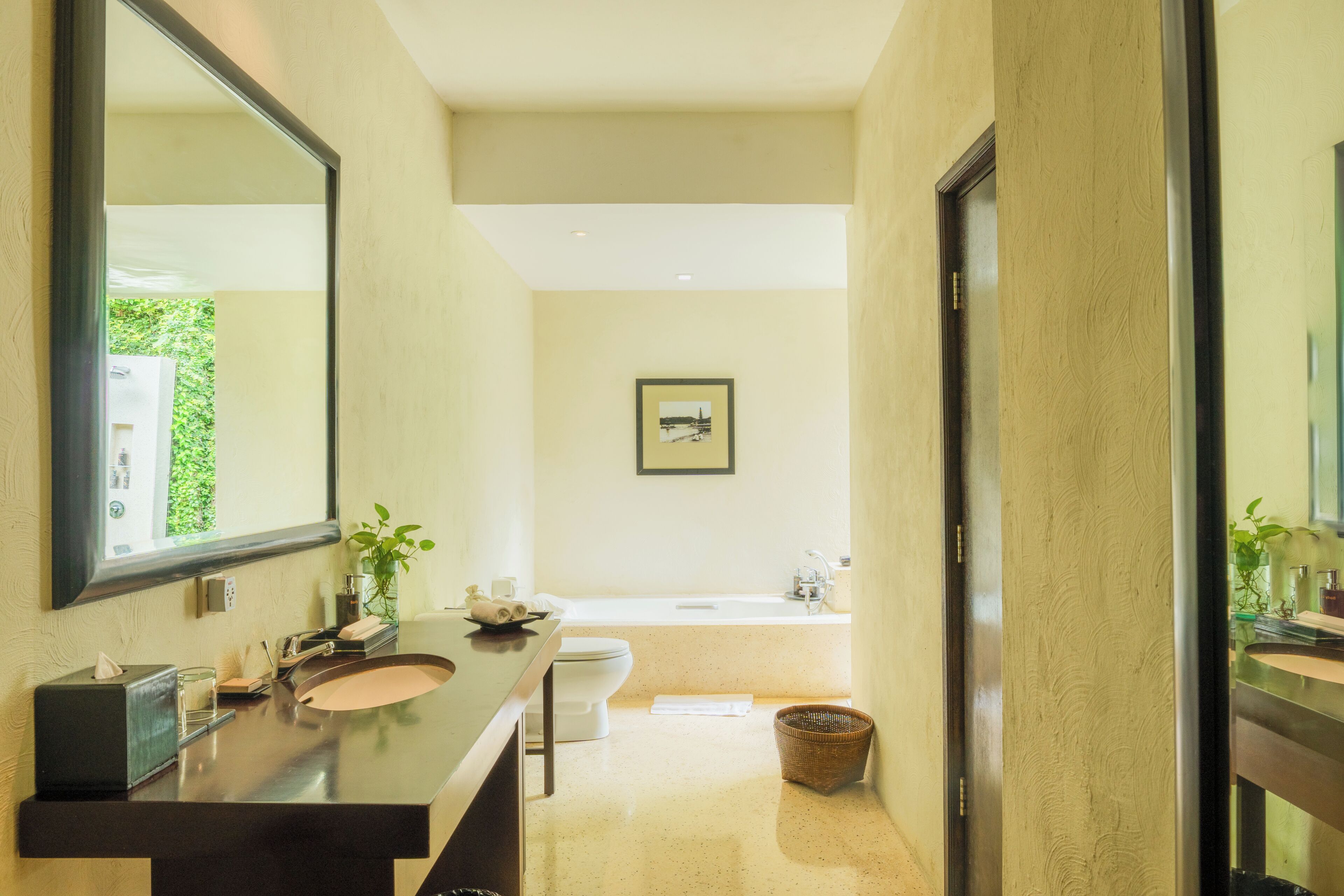 A modern bathroom with a large mirror, two sinks, a toilet, and a bathtub.