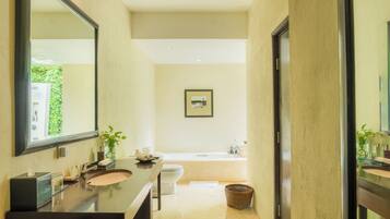 A modern bathroom with a large mirror, two sinks, a toilet, and a bathtub.