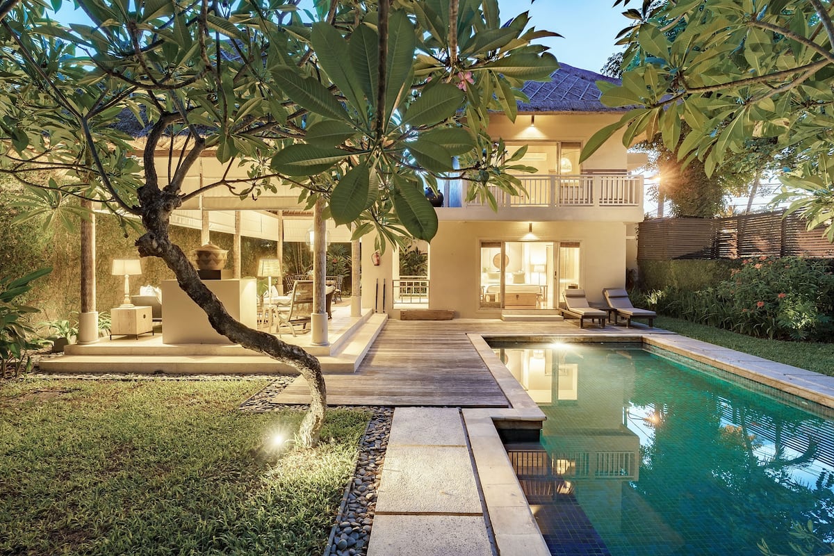 A two-story house with a swimming pool, a wooden deck, and a well-maintained garden.