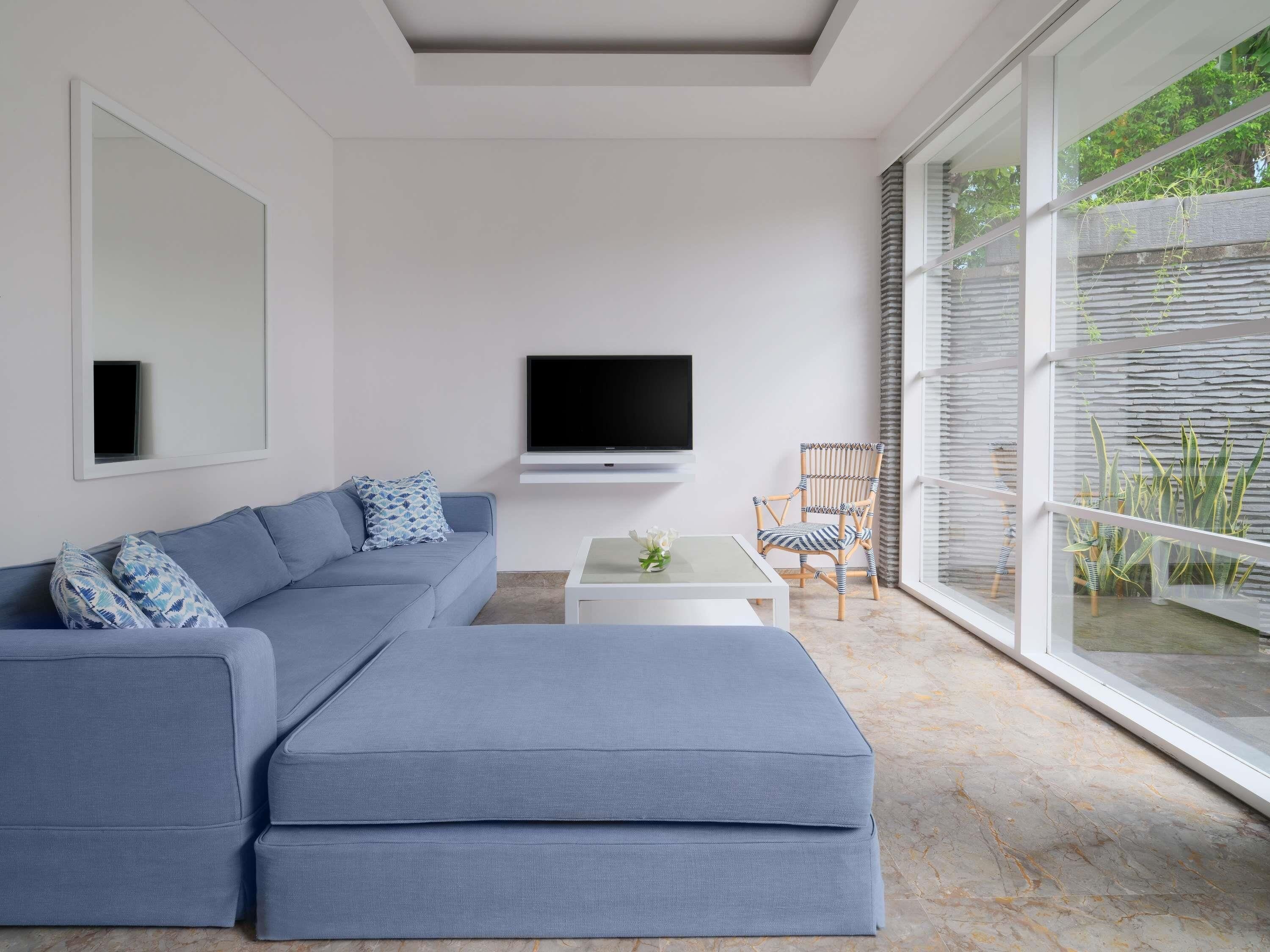 A modern living room with a sectional sofa, a flat-screen TV, a coffee table, and a chair.