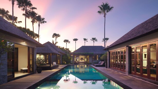 A poolside view of a resort with multiple overwater bungalows, a clear pool, and palm trees. - Peppers Seminyak (Seminyak)